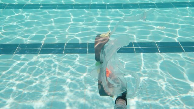 The snorkel mask is lost and sinks to the bottom of the pool. Swimming pool and camera under water. Slow motion
