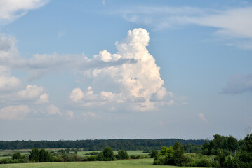 Thunderclouds on a summer day and a road in the countryside. A thunderstorm on a bright day.