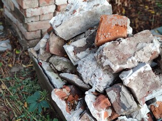 brick wall. The bricks are red, old, stacked in a cube. A lot of used building bricks. Building materials.