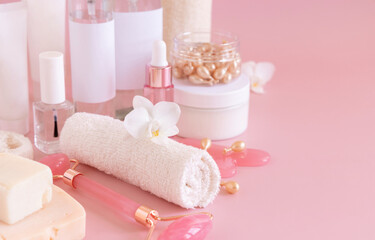 Natural cosmetic jars and skin care accesories with white orchid flower on pink close up, copy space