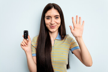 Young caucasian woman holding car keys isolated on blue background smiling cheerful showing number five with fingers.