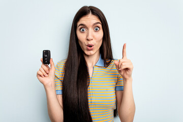 Young caucasian woman holding car keys isolated on blue background having some great idea, concept...