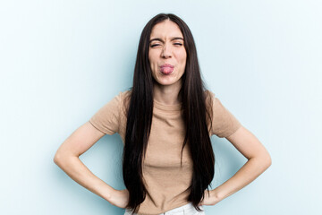 Young caucasian woman isolated on blue background funny and friendly sticking out tongue.