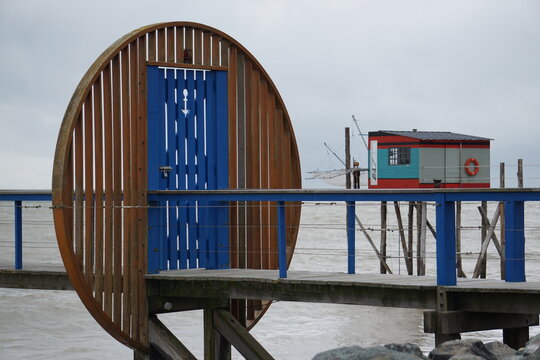 wooden pier over the ocean with unusual door and colorful  fishing hut in brittany france