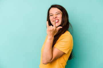 Young caucasian woman isolated on blue background showing rock gesture with fingers