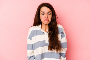Young caucasian woman isolated on pink background shrugs shoulders and open eyes confused.