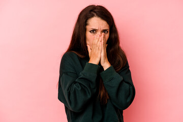 Young caucasian woman isolated on pink background covering mouth with hands looking worried.