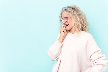Middle age caucasian woman isolated on blue background relaxed thinking about something looking at a copy space.