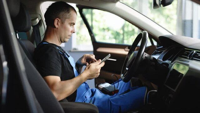 Car mechanic maintains the vehicle with the help of diagnostic modern computer equipment. Car service manager uses tablet computer with diagnostics software