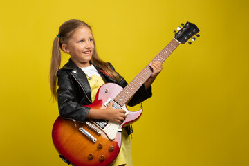 Caucasian girl child in a black rocker jacket leather with an electric guitar