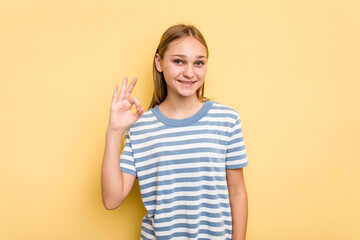 Young caucasian girl isolated on yellow background cheerful and confident showing ok gesture.