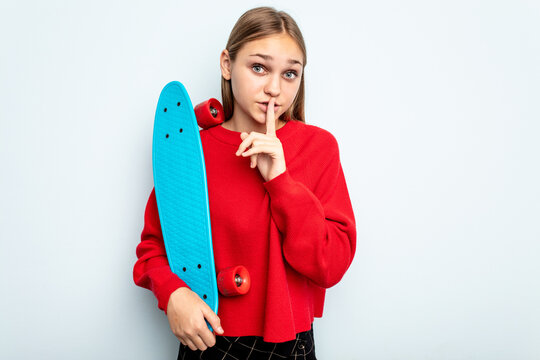 Young skater caucasian girl isolated on blue background keeping a secret or asking for silence.