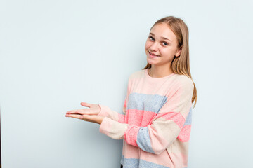 Young caucasian girl isolated on blue background holding a copy space on a palm.