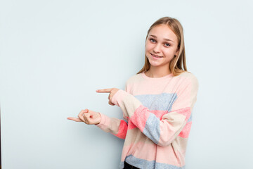 Young caucasian girl isolated on blue background excited pointing with forefingers away.