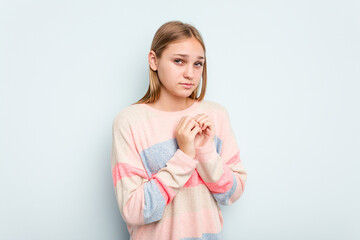 Young caucasian girl isolated on blue background scared and afraid.