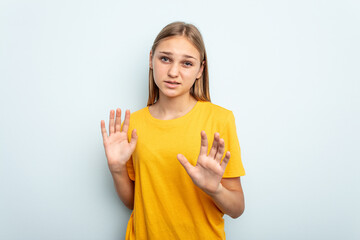 Young caucasian girl isolated on blue background rejecting someone showing a gesture of disgust.