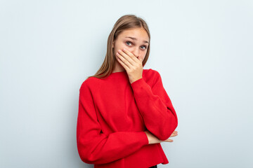 Young caucasian girl isolated on blue background scared and afraid.