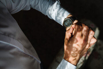 Man in a shirt adjusts the watch on his arm. Close up of businessman using watch. Top view.