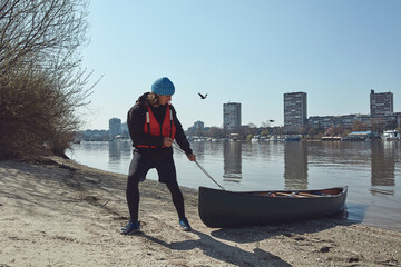 Man paddling with a canoe on a Danube river in urban area, small recreational escape, hobbies and sports outdoors.