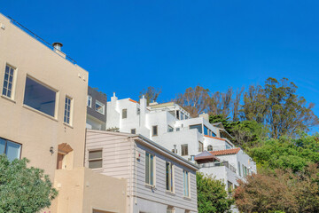 Fototapeta na wymiar Row of single-family houses along with an apartment building near a slope in San Francisco, CA