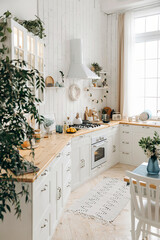 Modern large white Scandinavian kitchen with large window. Light stylish kitchen interior with kitchen accessories. Gas stove, cooking hood, built-in oven. Empty space.