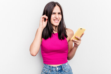 Fototapeta premium Young caucasian woman holding mobile phone isolated on white background covering ears with hands.