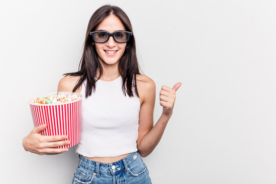 Young caucasian woman eating popcorn isolated on white background smiling and raising thumb up