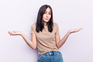 Young caucasian woman isolated on pink background doubting and shrugging shoulders in questioning gesture.