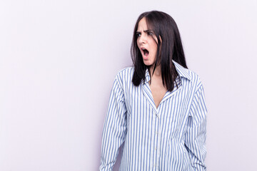 Young caucasian woman isolated on pink background shouting very angry, rage concept, frustrated.