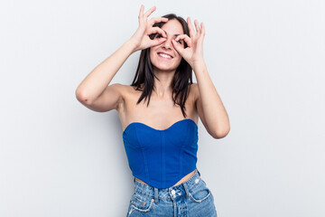 Young caucasian woman isolated on white background showing okay sign over eyes