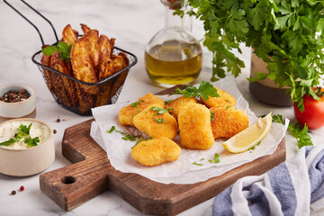 Nuggets served with potato wedges and sauce. Fish and chips.