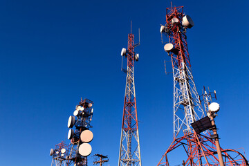 Several transmission and communication towers with blue sky in the background