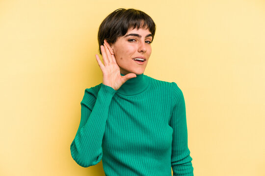 Young Caucasian Woman With A Short Hair Cut Isolated Trying To Listening A Gossip.