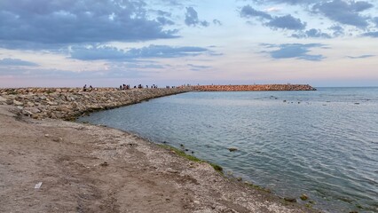 View of a concrete blocks and rocks dam in the Black Sea where people are taking a walk  - 522017688
