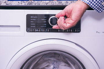 Mature man operates washing machine.