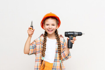 A little girl with an electric screwdriver in a protective orange construction helmet smiles...