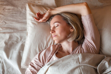 Middle aged woman sleeping in cozy bed