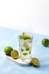 Delicious refreshing summer mojito with ice, lime and mint in a glass with grops. Sunshine. Copy space. Cold lemonade, tonic.