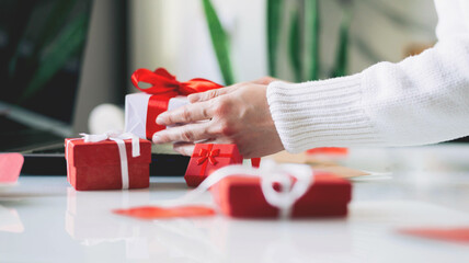 Woman holds a credit card and gift in her hands opposite the laptop. Online shopping. Valentine's Day gifts. 14 February on COVID-19 pandemic. Home delivery. Shopping online during holidays. Isolation