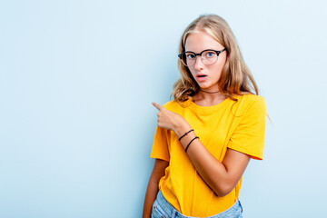 Caucasian teen girl isolated on blue background smiling and pointing aside, showing something at blank space.