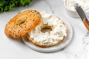 Bagel sandwich with cream cheese on marble board and white background