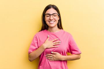 Obraz premium Young caucasian woman isolated on yellow background laughs happily and has fun keeping hands on stomach.