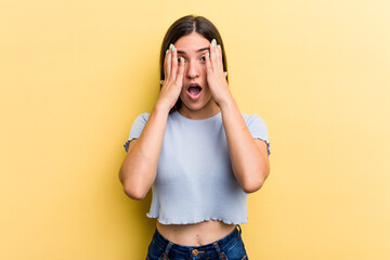 Young caucasian woman isolated on yellow background having fun covering half of face with palm.