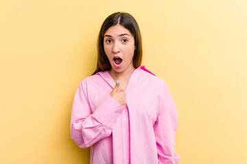 Young caucasian woman isolated on yellow background surprised pointing with finger, smiling broadly.