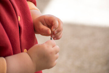 close up of a baby's hands playing with a twig, outside activity, fine motor skills development