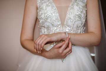 Girl put a bracelet on arm. bride putting on jewelry, focus on bracelet. Bridal preparation for the...