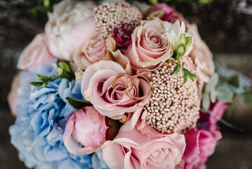 Wedding rings bride and groom on the background bridal bouquet with flowers roses and greenery.