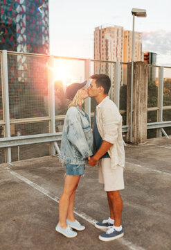 summer holidays, love and people concept - happy young couple kissing on roof top city parking