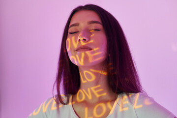 Conception of love. Beautiful young woman is in projector neon lights in the studio