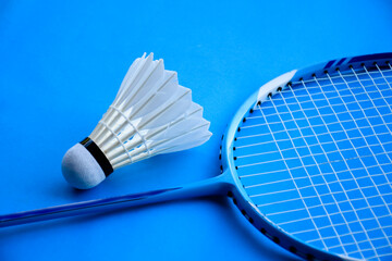 Badminton racket and badminton feather shuttlecock on blue floor of indoor badminton court, soft and selective focus, concept for playing badminton in daily life to get strong health and good feeling.